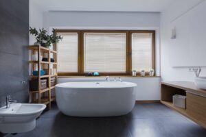 Spacious and comfortable bathroom with a freestanding bathtub in front of a set of closed blinds to block out the light from entering the room.