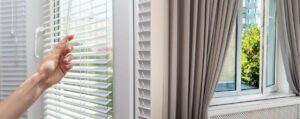 An image of a person opening their blinds and a set of curtains that are open slightly.