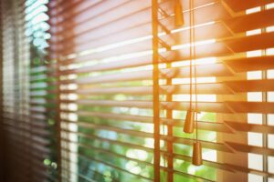 A set of open blinds with a ray from the sun entering the room.