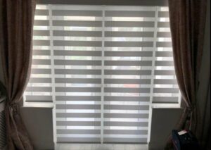 A set of day and night blinds that are fully closed to block out any light from entering the room.
