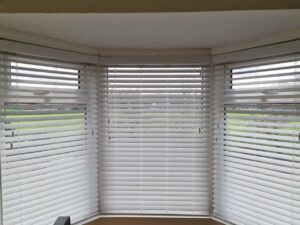 a pair of white Vinitian blinds set up on three window sills.