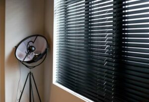 A pair of closed black blinds inside of a bedroom.