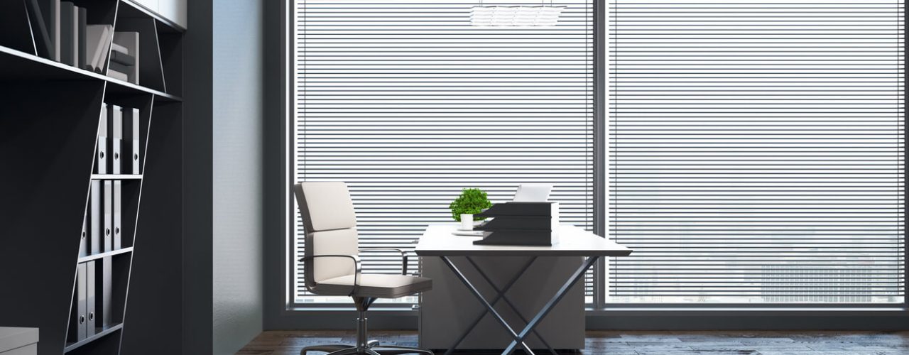 View of interior office blinds with a chair and a desk.