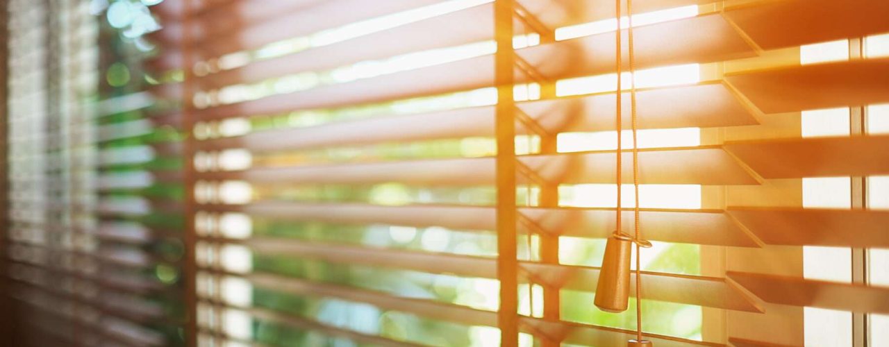 A set of open blinds with a ray from the sun entering the room.
