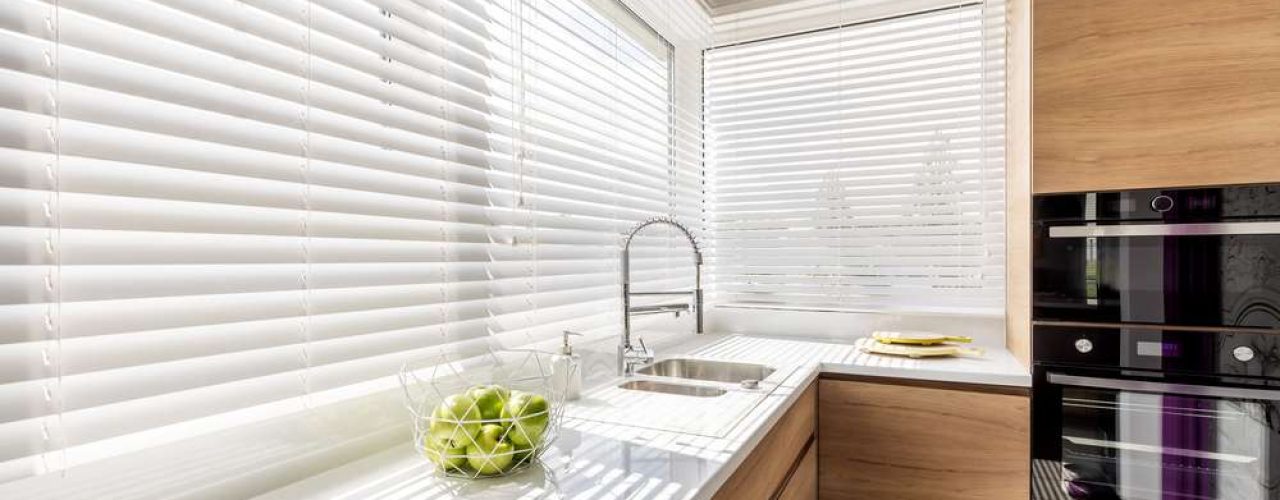 A pair of blinds set up on a set of kitchen windows.