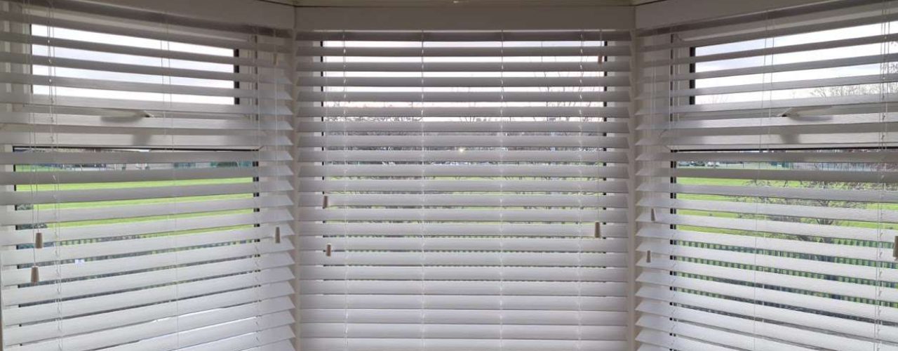 a pair of white Vinitian blinds set up on three window sills.