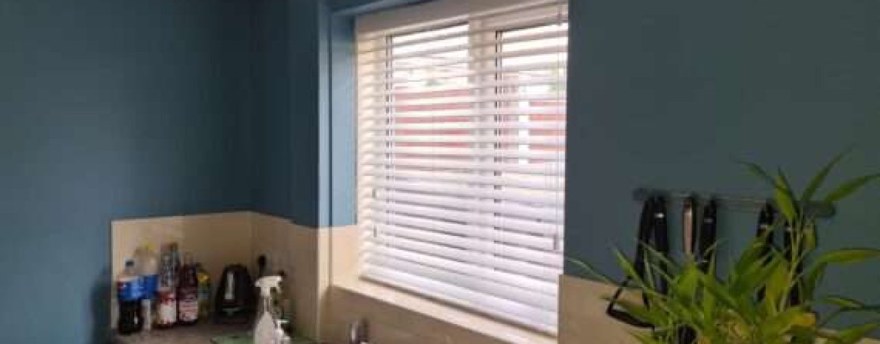 A set of blinds set up on a window sill underneath a sink.